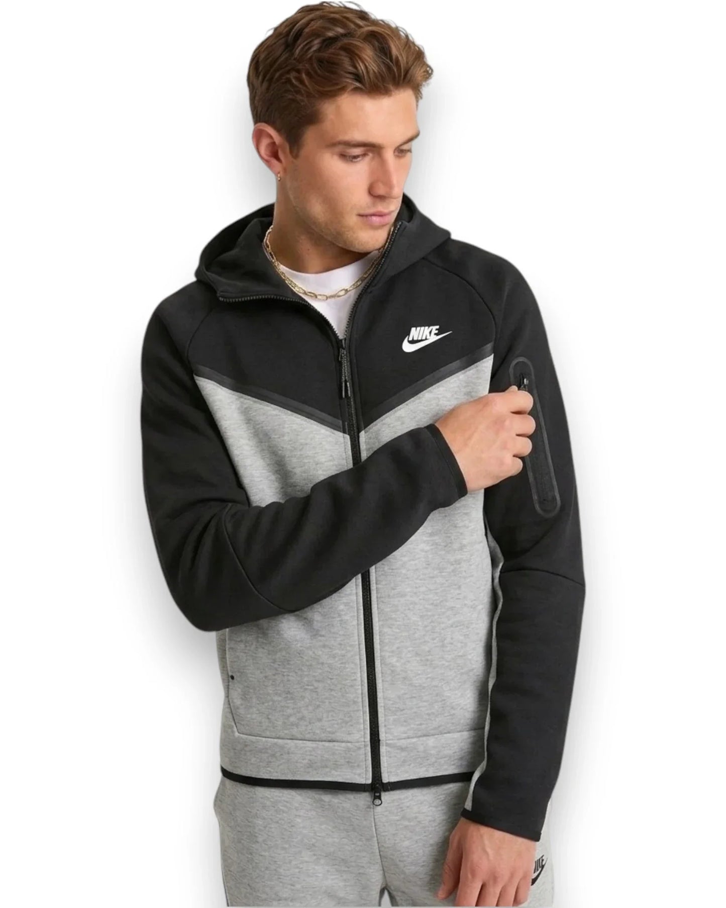 Man wearing a black and gray Nike Tech Fleece hoodie on a white background