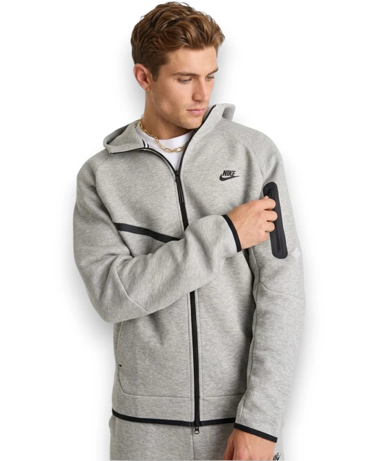 Man wearing a gray Nike tech fleece hoodie on a white background